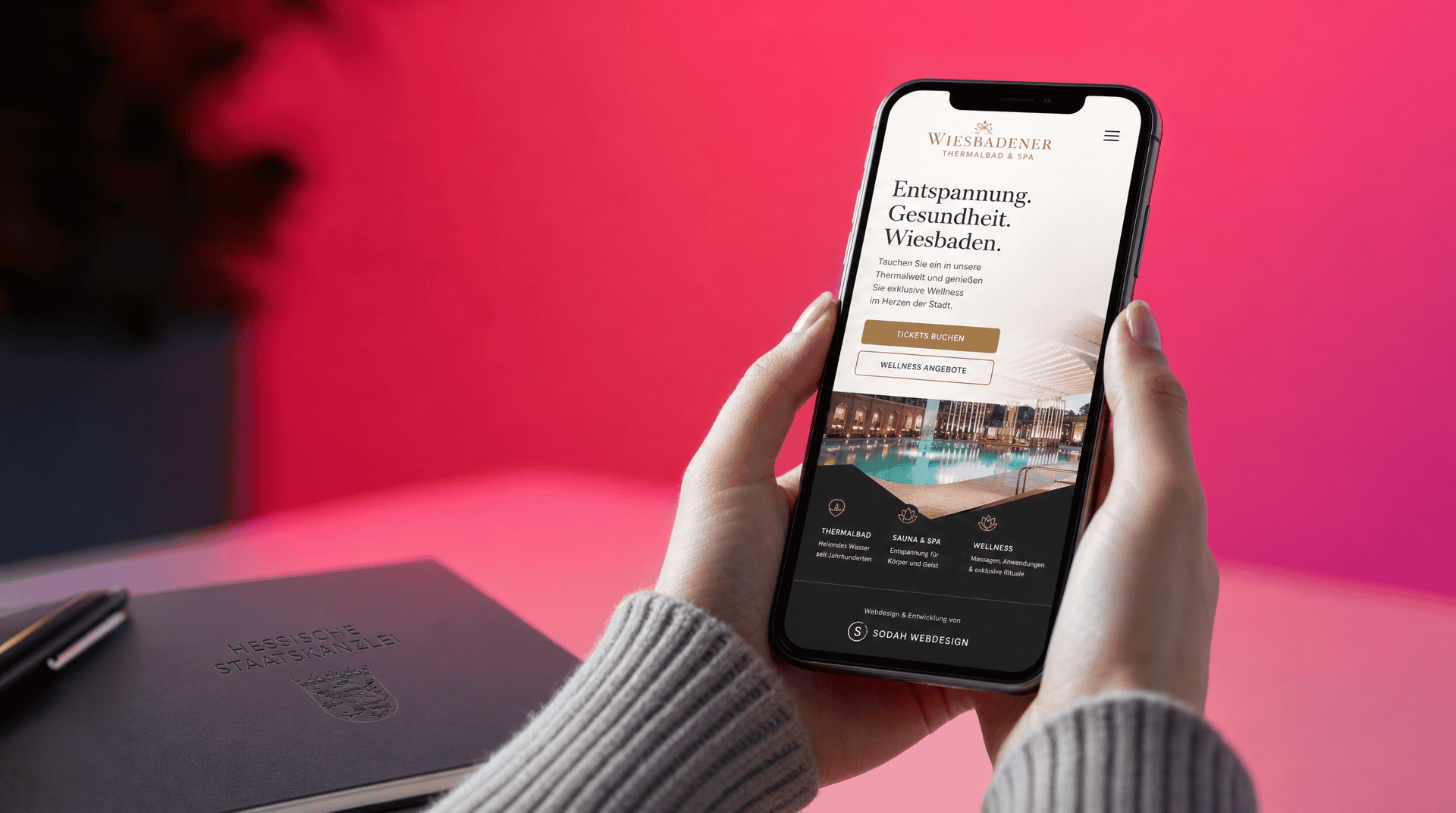 Hände halten Smartphone mit responsiver Website des Wiesbadener Thermalbads von Sodah Webdesign.