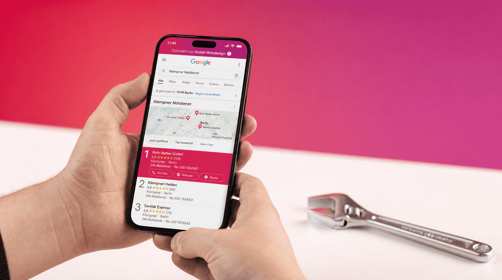 Hände halten Handy mit Google-Suche nach Klempner Notdienst, daneben ein Schraubenschlüssel.